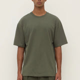 Person wearing a green t-shirt and pants against a white background