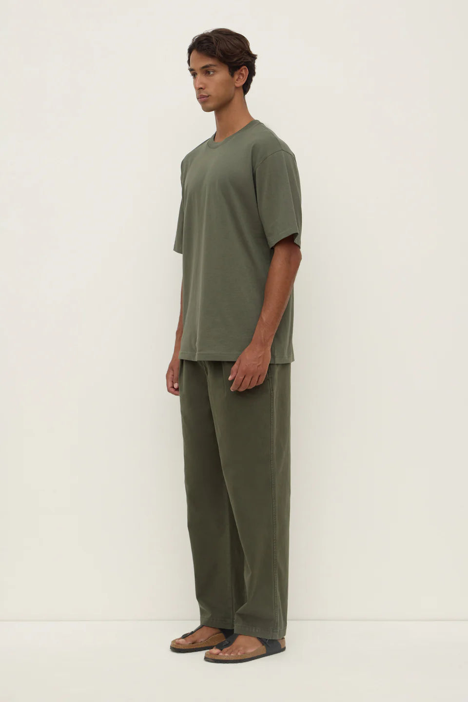 Man wearing a green outfit standing against a white background