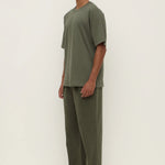 Man wearing a green outfit standing against a white background