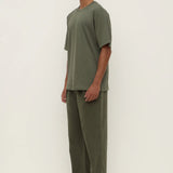 Man wearing a green outfit standing against a white background
