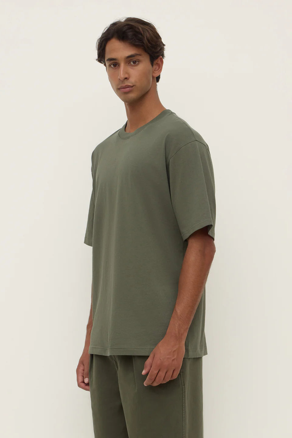 Man wearing a green t-shirt and pants against a white background