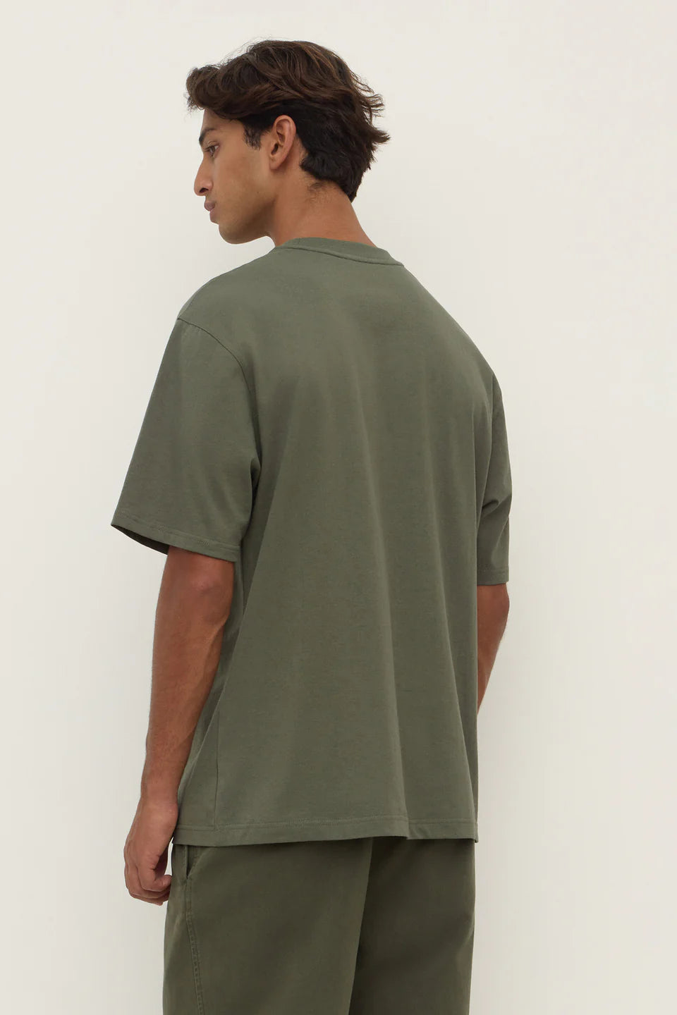 Person wearing a green t-shirt and pants against a white background