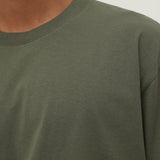 Close-up of a person wearing a green long-sleeve shirt against a neutral background