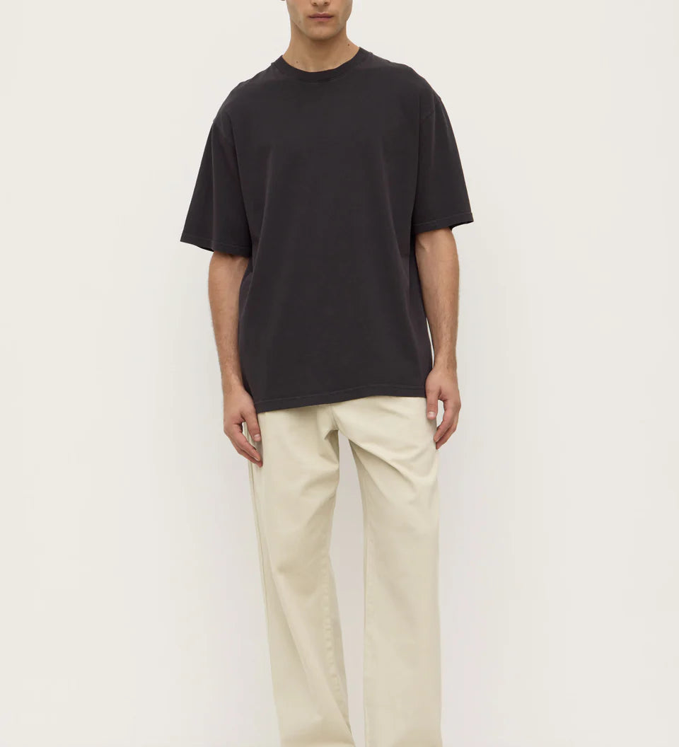 Person wearing a black t-shirt and beige pants on a white background