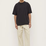 Person wearing a black t-shirt and beige pants on a white background