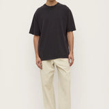 Person wearing a black t-shirt and beige pants on a white background