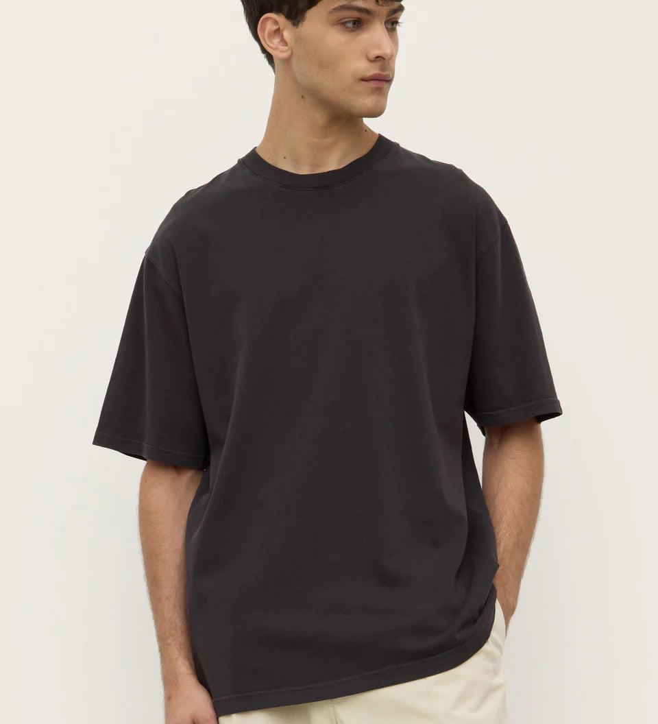 Man wearing a black t-shirt and beige pants against a white background