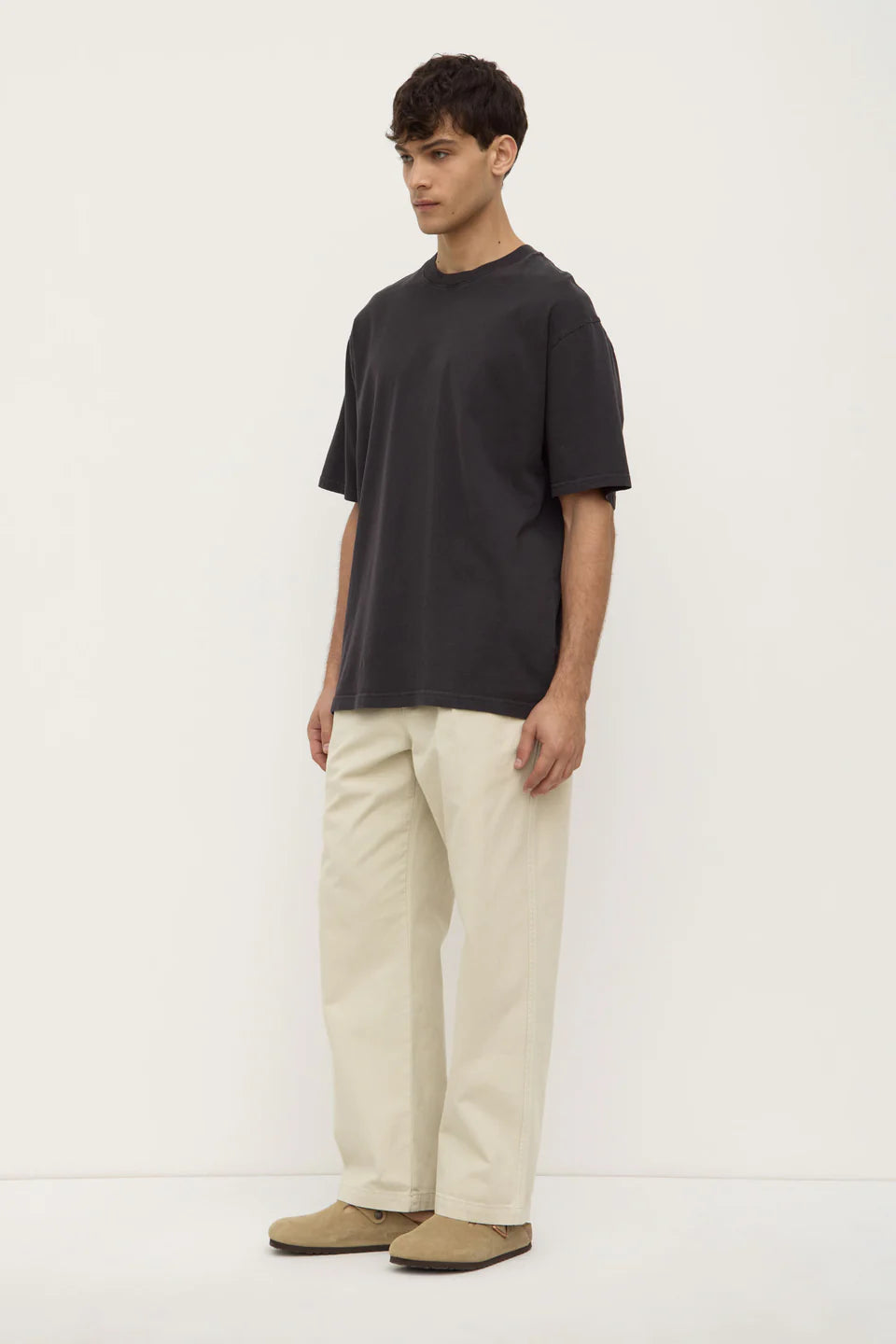 Man wearing a black t-shirt and beige pants on a white background
