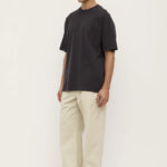 Man wearing a black t-shirt and beige pants on a white background