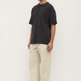 Man wearing a black t-shirt and beige pants on a white background
