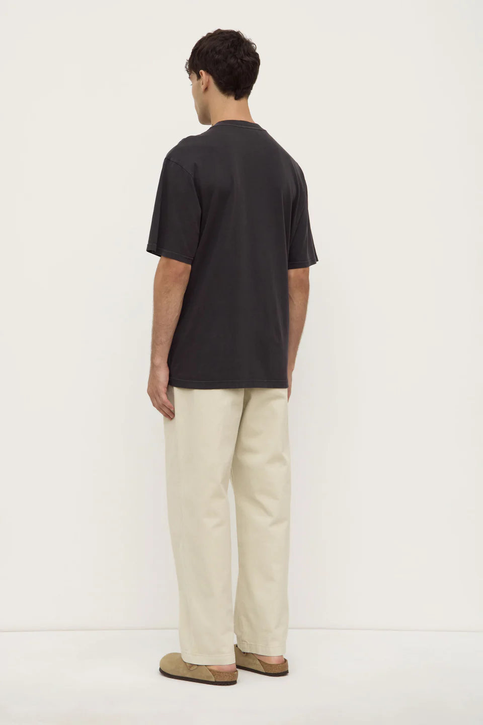Person wearing a black t-shirt and beige pants on a white background