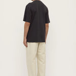 Person wearing a black t-shirt and beige pants on a white background