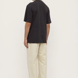 Person wearing a black t-shirt and beige pants on a white background