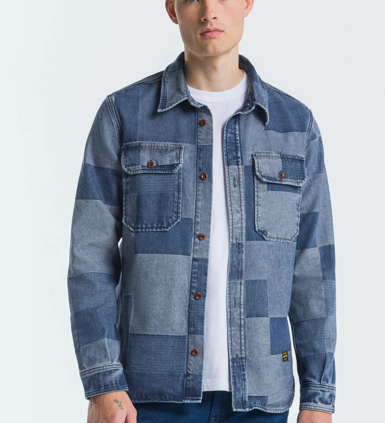 Man wearing a patchwork denim jacket on a white background