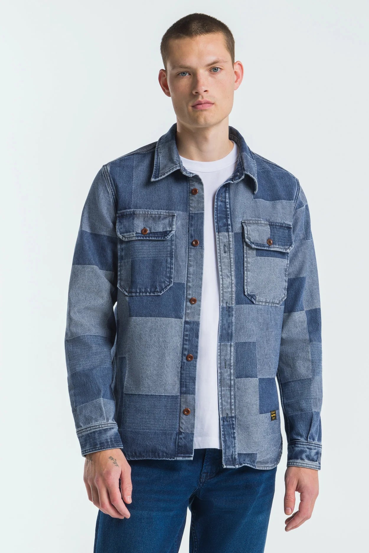 Man wearing a patchwork denim jacket on a white background
