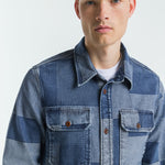 Man wearing a patchwork denim jacket on a white background