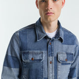 Man wearing a patchwork denim jacket on a white background