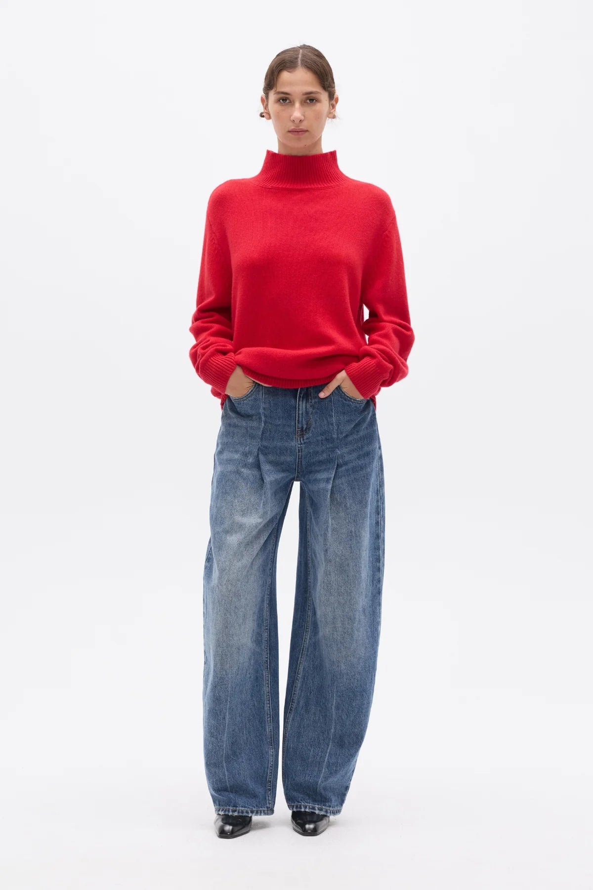 Person wearing a red sweater and blue jeans on a white background