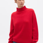 Person wearing a red turtleneck sweater on a white background