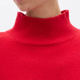 Close-up of a person wearing a red turtleneck sweater against a white background