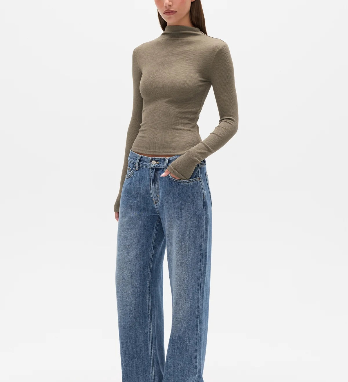 Woman wearing a brown turtleneck and blue jeans on a white background