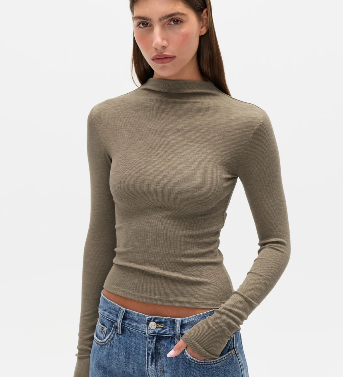 Woman wearing a green turtleneck sweater and blue jeans on a white background