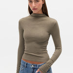 Woman wearing a green turtleneck sweater and blue jeans on a white background