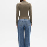 A woman viewed from the back wearing a fitted olive-brown long-sleeve mock-neck top and wide-leg blue jeans against a plain white studio background.