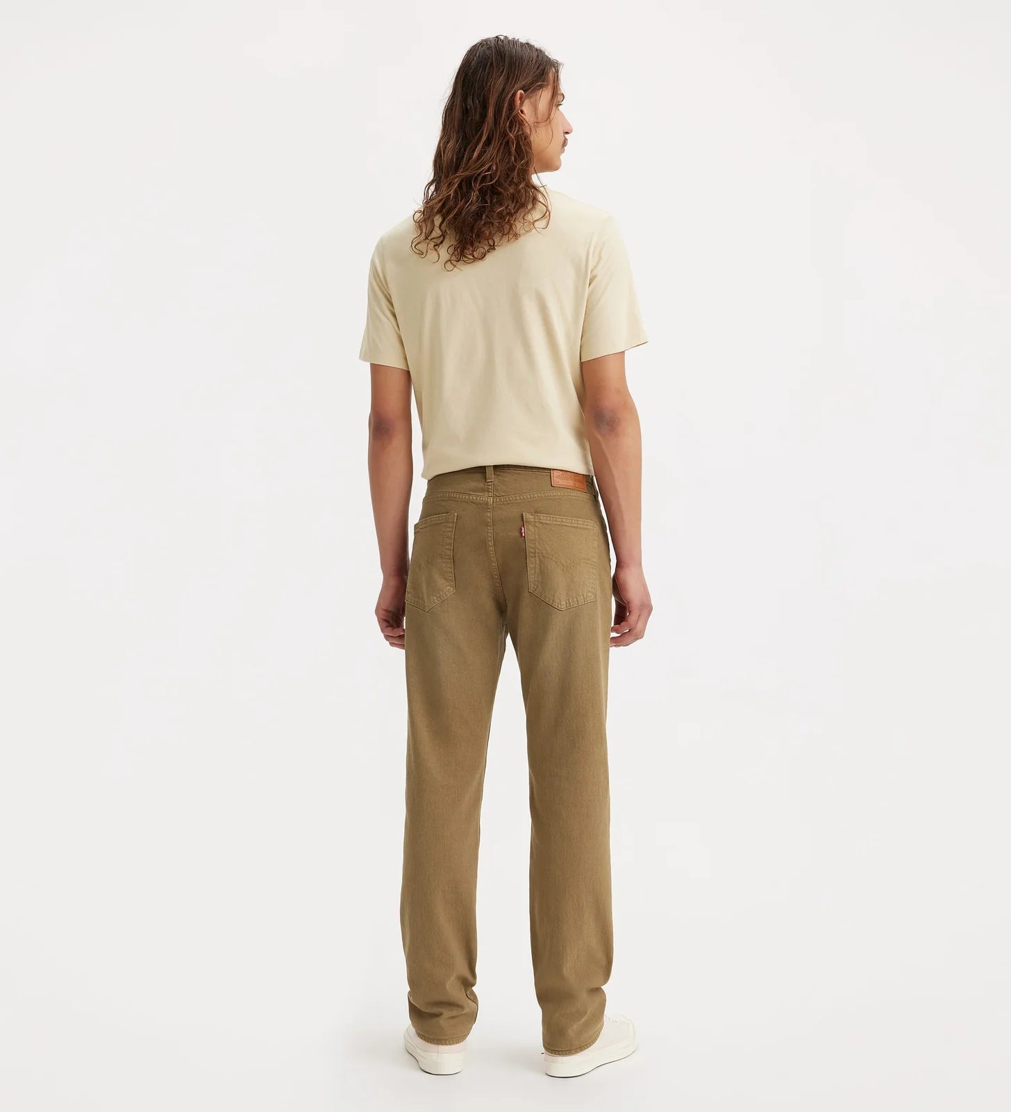 A model shown from the back wearing a light beige short-sleeve t-shirt and brown straight-leg jeans, standing against a plain white studio background.