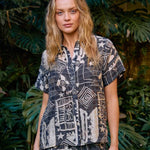 Woman in a patterned outfit standing in a garden setting