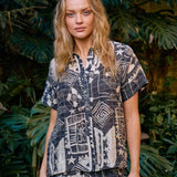 Woman in a patterned outfit standing in a garden setting