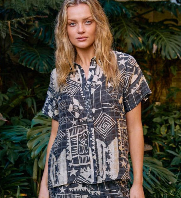 Woman in a patterned outfit standing in a garden setting
