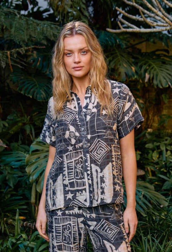 Woman in a patterned outfit standing in a garden setting