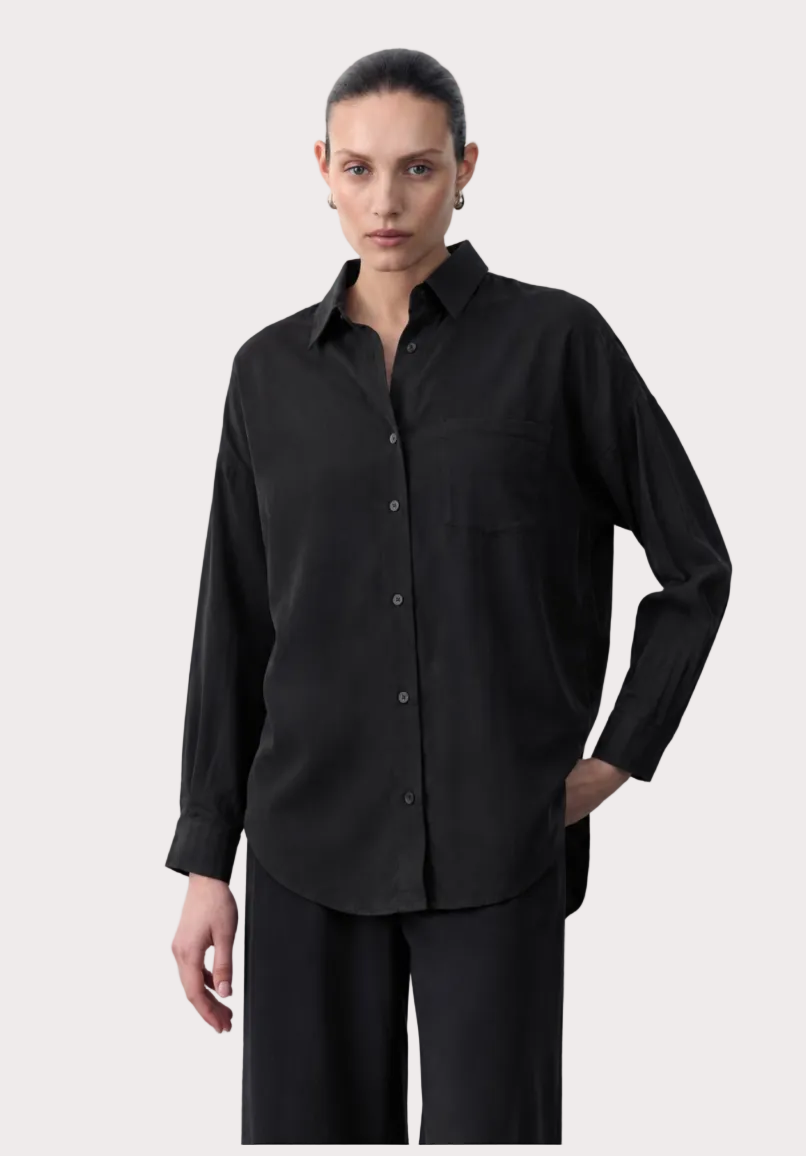 Woman wearing a black tencel shirt with product details on a white background