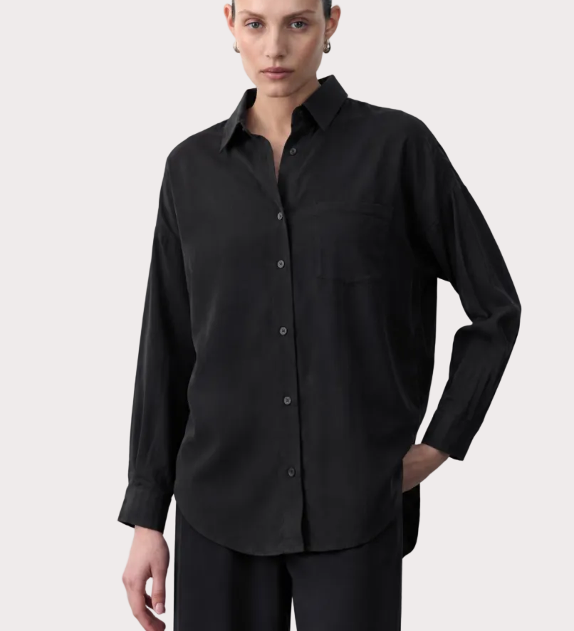 Woman wearing a black tencel shirt with product details on a white background