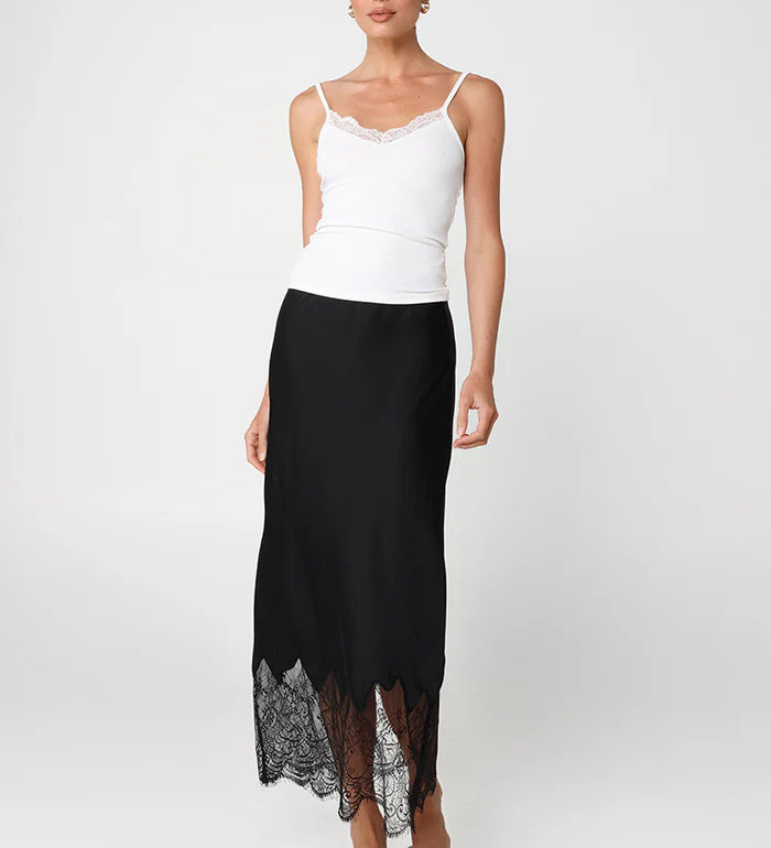 Woman wearing a white top and black skirt with lace hem on a white background