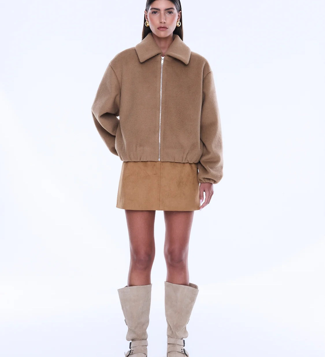 Woman wearing a beige jacket and skirt with knee-high boots on a white background