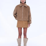 Woman wearing a beige jacket and skirt with knee-high boots on a white background