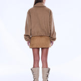 Person wearing a beige jacket and skirt set with high-heeled boots on a white background