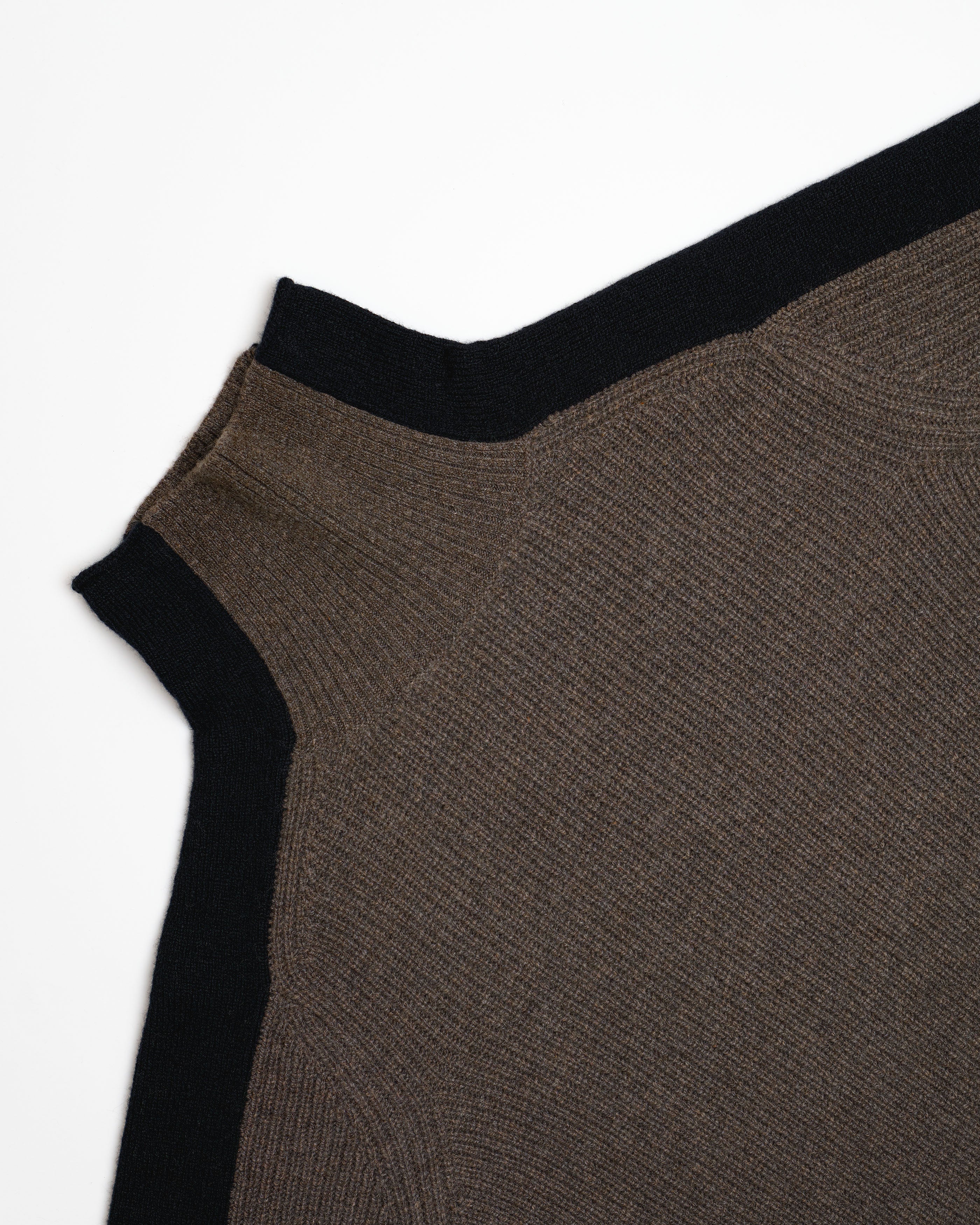 Close-up of a ribbed knit garment corner showing a dark brown body with black ribbed trim on a plain white background.