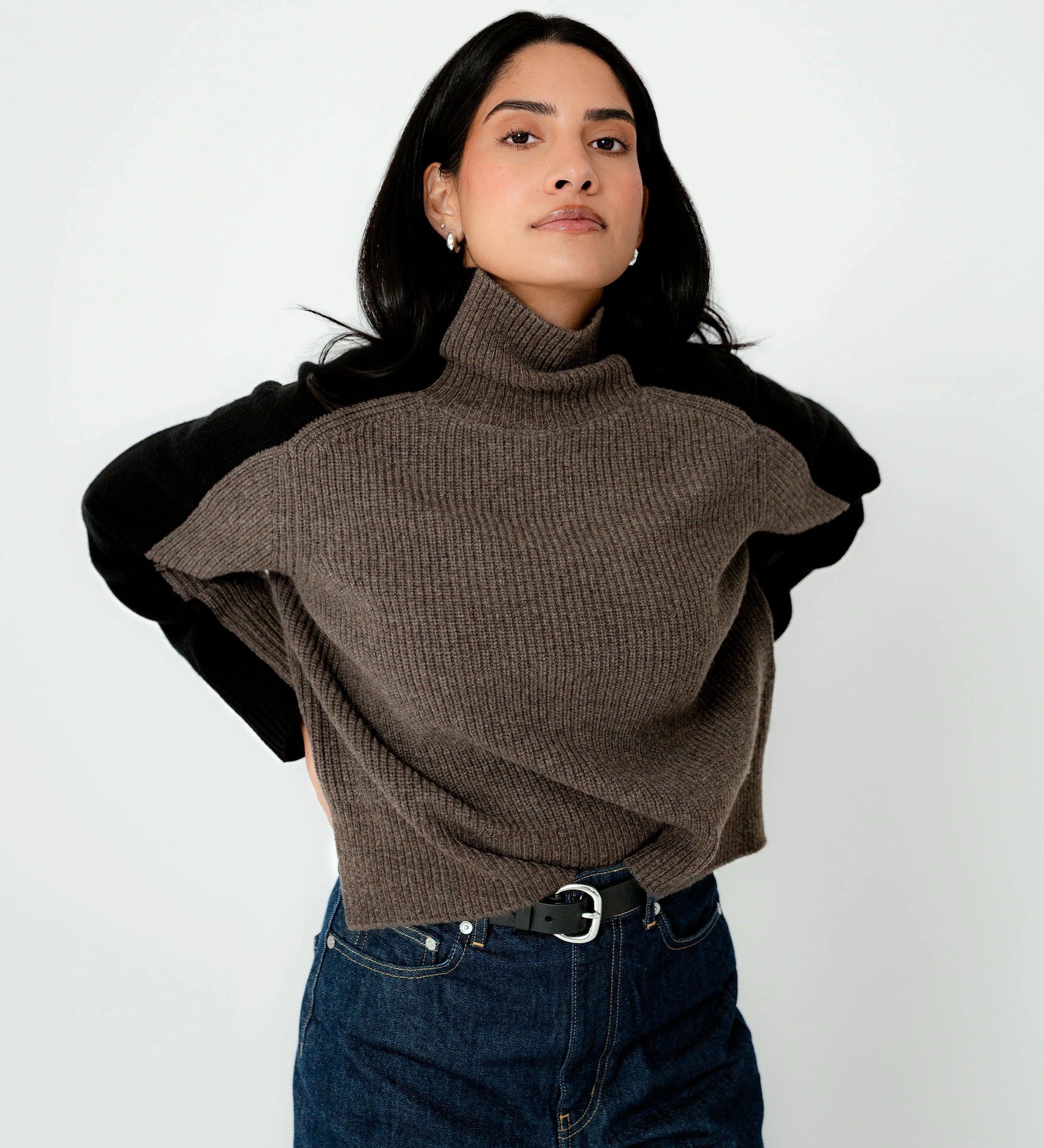 Woman wearing a brown turtleneck sweater with black sleeves on a white background