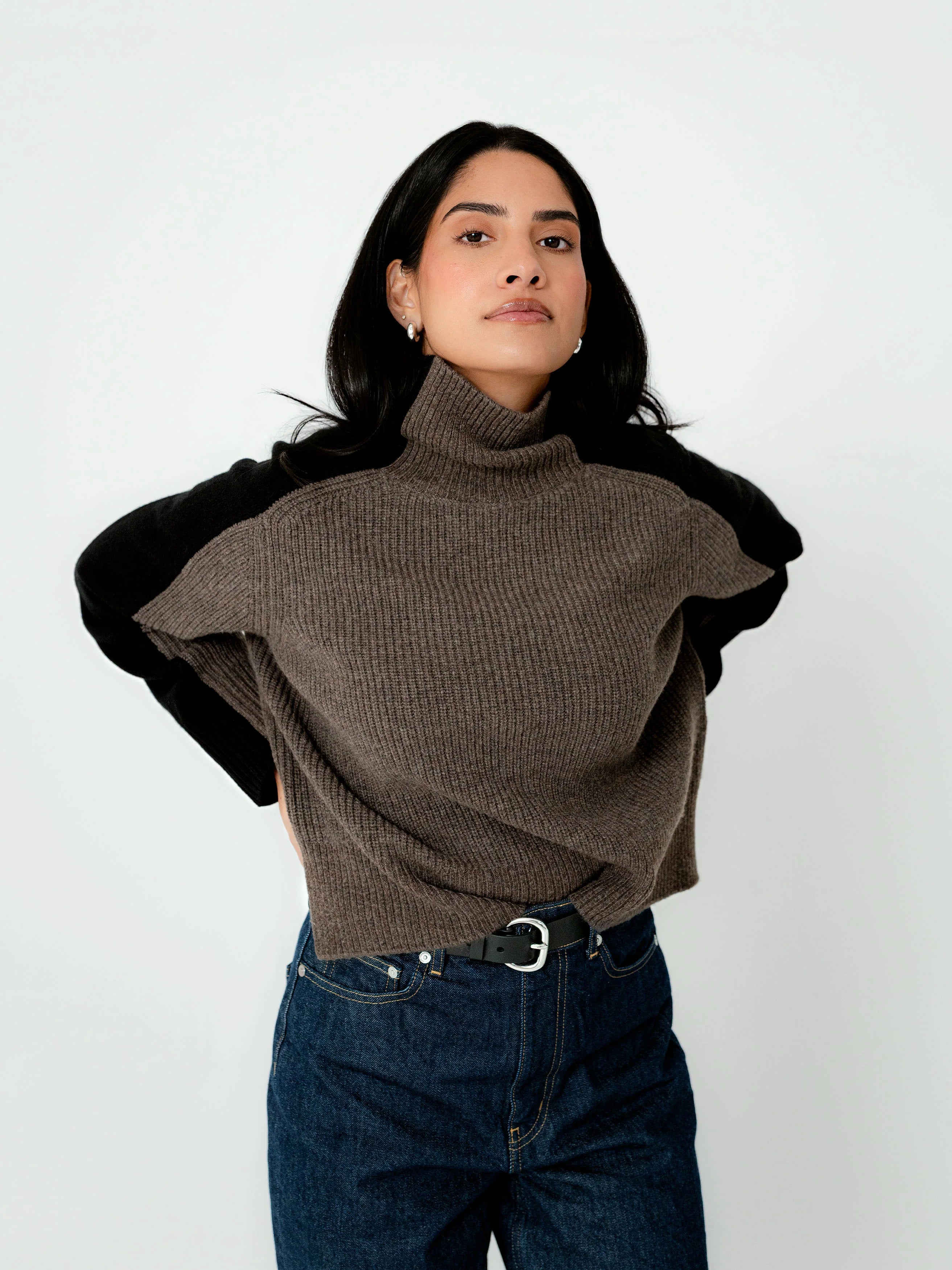 Woman wearing a brown turtleneck sweater with black sleeves on a white background