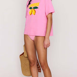 Woman wearing a pink t-shirt with a yellow graphic design on a plain background