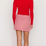 Person wearing a red long-sleeve top and pink checkered skirt on a white background