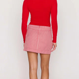 Person wearing a red long-sleeve top and pink checkered skirt on a white background