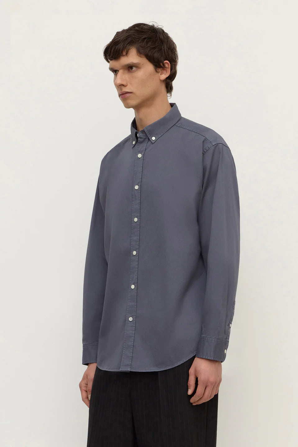 Man wearing a gray button-up shirt against a white background