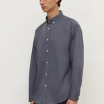 Man wearing a gray button-up shirt against a white background