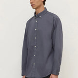 Man wearing a gray button-up shirt against a white background