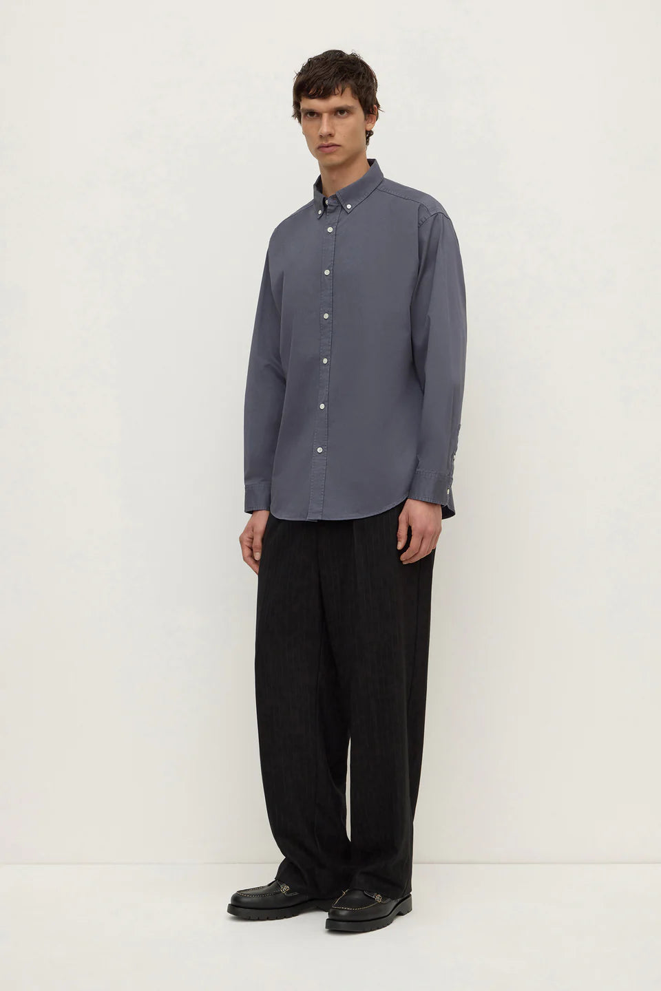 Man wearing a gray shirt and black pants on a white background