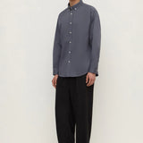 Man wearing a gray shirt and black pants on a white background